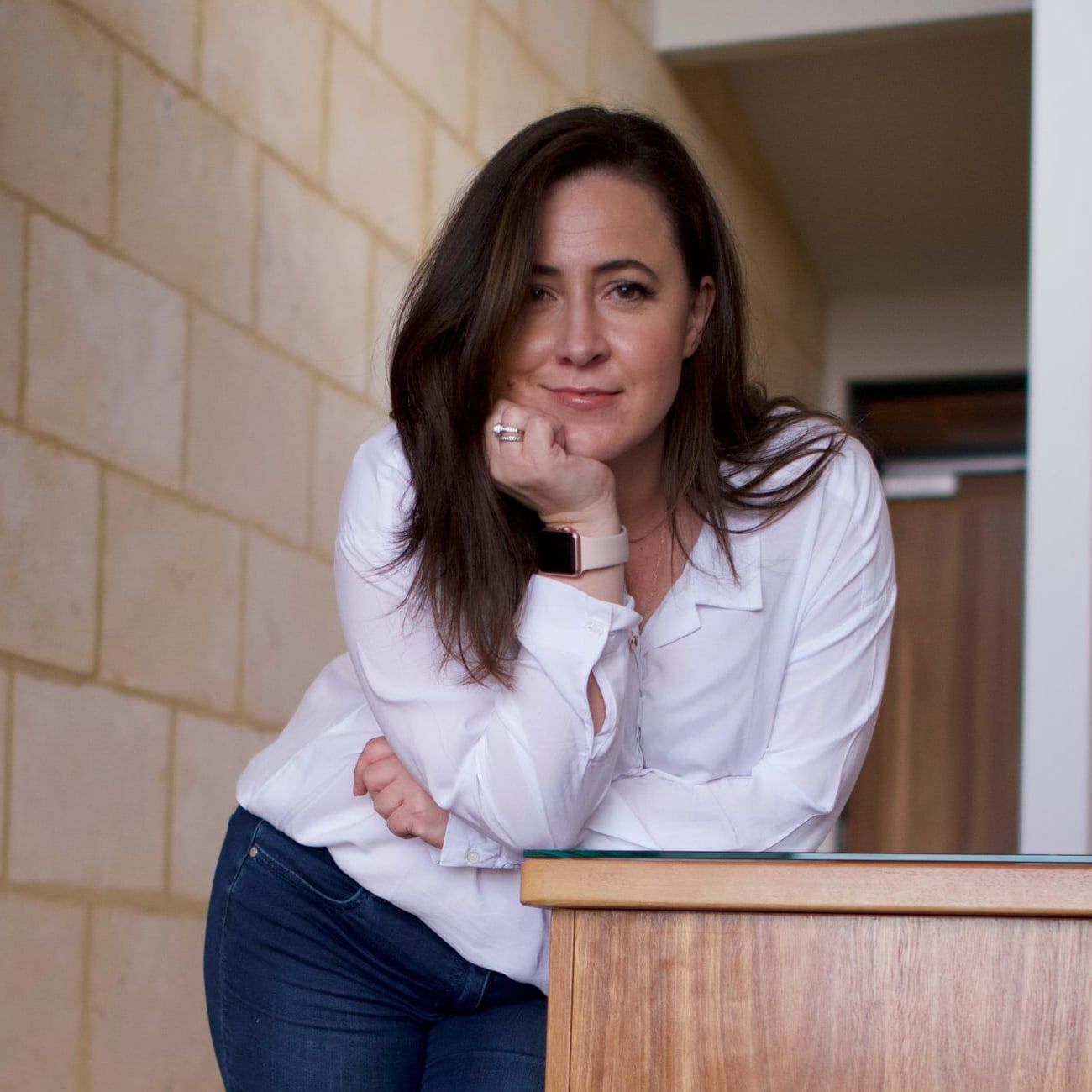Jessica Kidner, beauty business coach, smiling and leaning on a timber counter