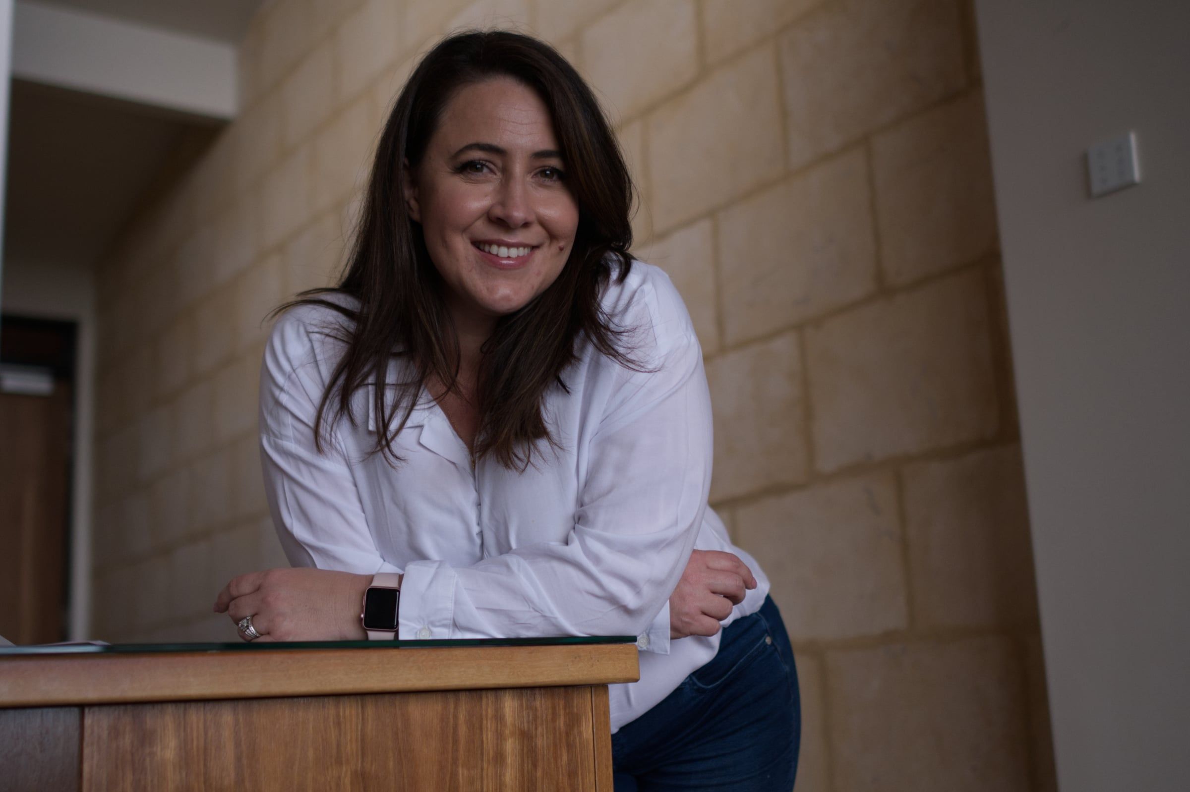 Jessica Kidner smiling, leaning on a timber counter