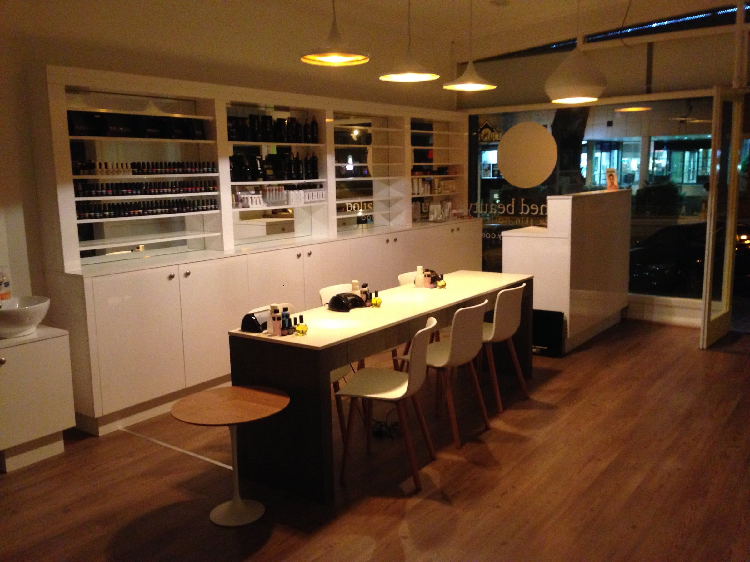 The finished salon at night, with a long nail bar and lit shelves